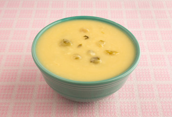 Bowl of cream of celery soup on table cloth