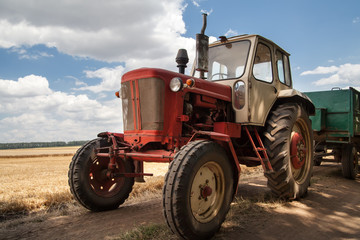 Obraz premium old tractor on the field, against a cloudy sky