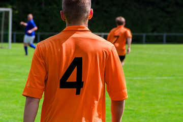 Fußballspieler im orangen Trikot von hinten 