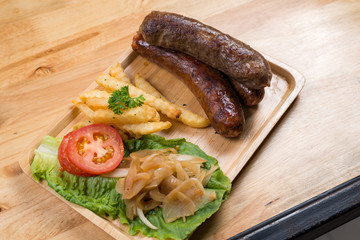 Sausages on wooden plate on wooden table