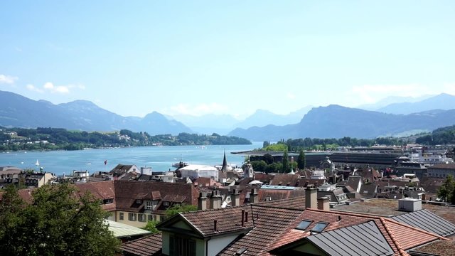 Pan over the roofs of Lucerne switzerland with the beautiful mountains and  its lake in the background.