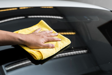 Car polishing series : Hand of worker using yellow towel wiping windshield