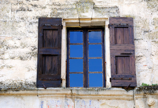 Open window of French house with wooden shutters. 