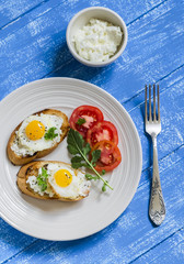 toast with feta cheese and fried quail egg, fresh tomatoes on a  wooden surface - a healthy Breakfast or snack