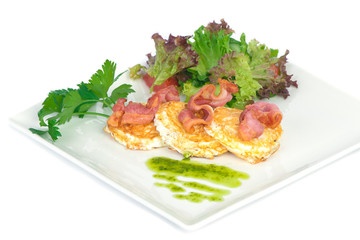 fried eggs with bacon and green salad on the white plate