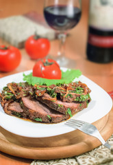 Beef sliced with a sauce of grilled onions and parsley on a white plate