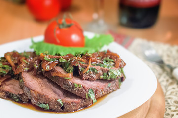 Beef sliced with a sauce of grilled onions and parsley on a white plate