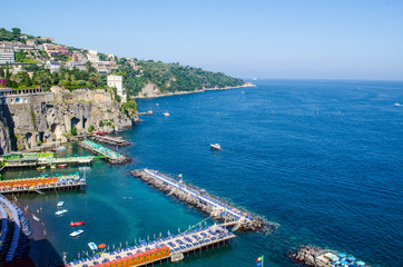 view of coast of italian city sorrento where people may relay on a wooden quay offseting sandy...