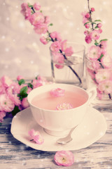 Fototapeta na wymiar Cup of tea and beautiful fruit blossom on table