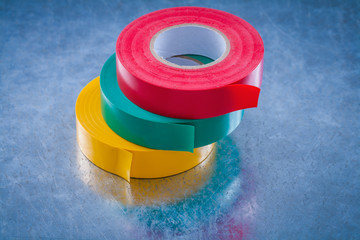 Rolls of insulating tapes on scratched metallic surface construc