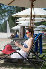 Asian woman using smart phone on beach chair