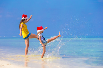 Little girl and young mother in Santa Hat during beach vacation