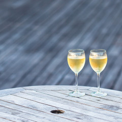 Two glasses of tasty white wine at sunset on wooden table