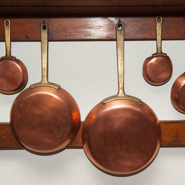 Vintage copper pans hung on wooden shelf