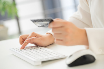 Hands of an office woman typing keyboard with credit card