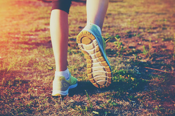 Girl jogging outside. Feet running on grass