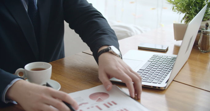 Hands of businessman working on laptop at café 