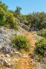 Mediterranean rocky landscape with a footpath of red earth throu