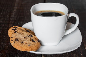 кофе в белой чашке с печеньем на деревянном столе