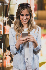 Beautiful woman writting a message on her phone while doing shopping.