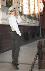 a young man in fashionable clothes strolls on city street
