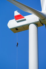Brave Technician worker roping down on a very high wind generator. The Weather is fine and the sun...