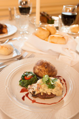 A restaurant dinner of steak and baked potato with bread and red