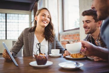 Smiling friends enjoying coffee and using at tablet
