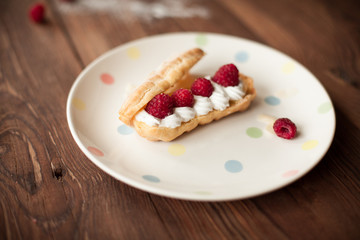 Sweet dessert with fresh raspberries on plate on wood table