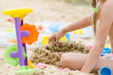 The girl builds a sand castle wall