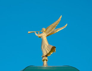 Fototapeta premium Golden angel with a trumpet on a background of blue sky