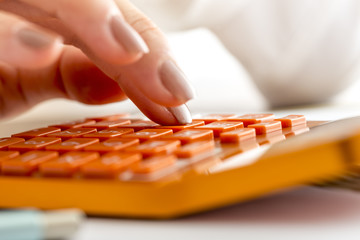 Female accountant or banker making calculations on orange desk c