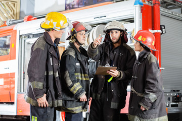 Firefighter Showing Something To Colleagues At Fire Station