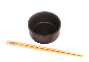 Black ceramic bowl with wooden shopsticks isolated