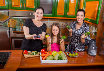 Mother, daughter and aunt preparing dinner in the kitchen and have fun