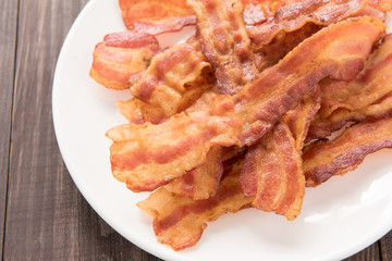Closeup of fried bacon strips on white plate