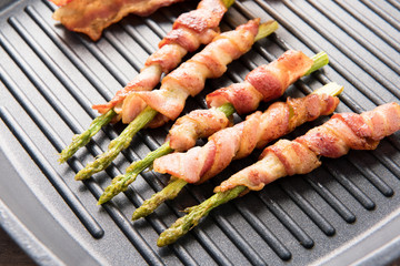 Bacon slice and asparagus wrapped in bacon being cooked in fryin