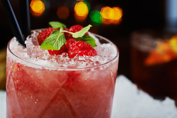 bright beautiful and tasty alcoholic cocktail or lemonade with a cap of frozen ice, mint and fresh raspberries