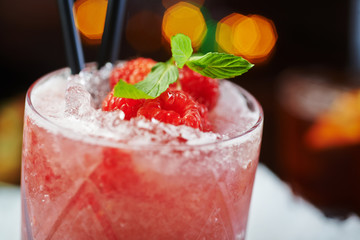 bright beautiful and tasty alcoholic cocktail or lemonade with a cap of frozen ice, mint and fresh raspberries