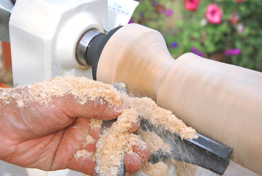 Carpenter handle wooden cylinder on lathe with chisel