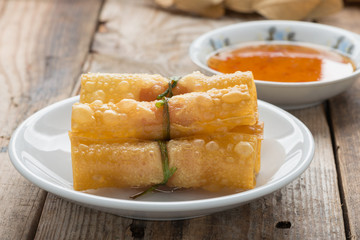 Fried wonton with sauce on wood table.