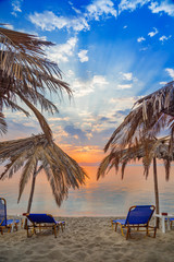 Vivid sunrise on a beautiful sandy beach with sunshade
