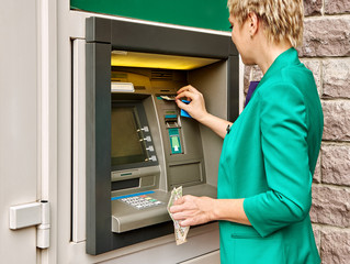 Business woman operates ATM