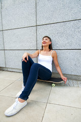Young modern girl sit on skateboard by the wall in the city look © Wisiel