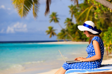 young woman with laptop on tropical beach