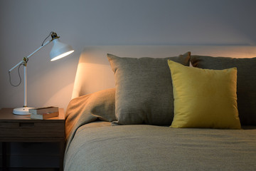 Cozy bedroom interior with pillows and reading lamp on bedside t