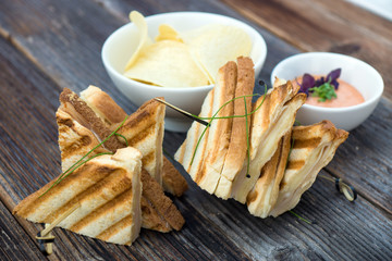 Toast sandwiches with ham on the wooden board.