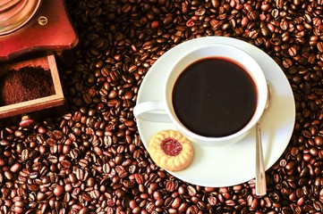 Kaffeetasse und Kaffeemühle auf Kaffebohnen als Hintergrund, Kaffeewerbung