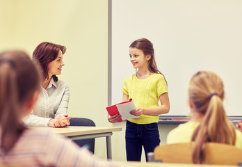 group of school kids with teacher in classroom