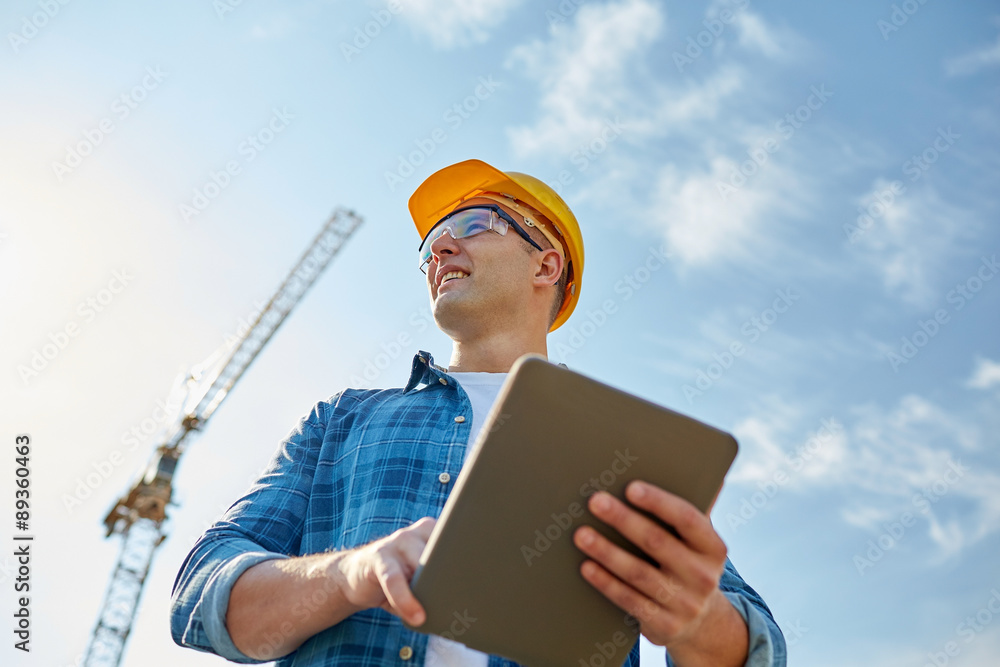 Poster builder in hardhat with tablet pc at construction